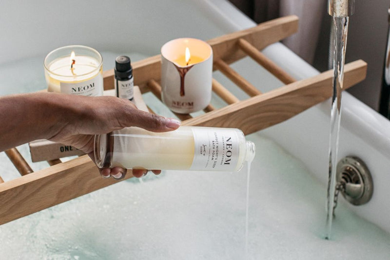 NEOM skincare products on wooden bath shelf