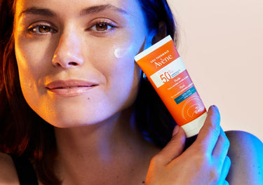 smiling lady holding an Avène sunscreen