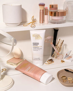 Bondi Sands Gradual Tan Lotion Illuminator on a countertop surrounded by makeup